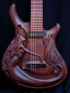 an intricately carved wooden guitar with a mermaid on it's back and sides