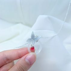 a hand holding a tiny glass ball with a butterfly on it's side and a red bead in the middle