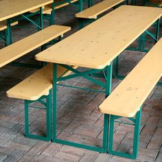 several wooden benches are lined up against each other on the brick floor in an empty room