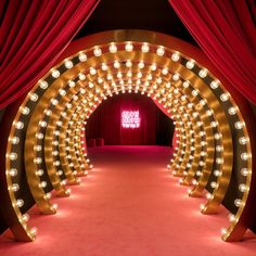 a red carpeted area with lights and curtains on the walls, leading to a stage