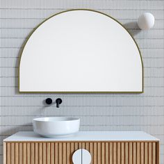 an oval mirror above a sink in a bathroom