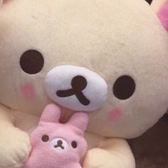 a white teddy bear holding a pink stuffed animal