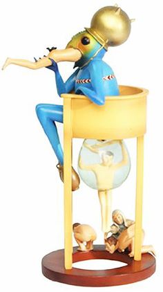 a figurine sitting on top of a table with an instrument in its mouth