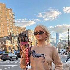 a woman holding a small dog in her hands while standing on the side of a road