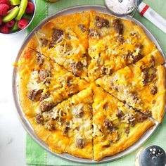 a pizza sitting on top of a metal pan covered in cheese and meat toppings