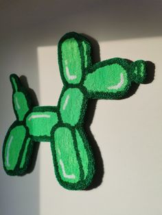 a close up of a stuffed animal on a white surface with green paint and black trim