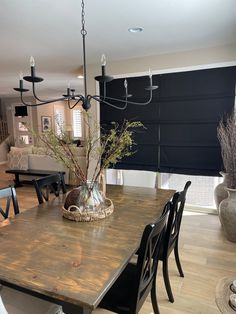 a dining room table with black chairs and a vase on top of the wooden table