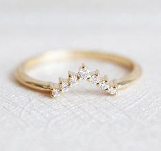 a gold ring with three small diamonds on the top and bottom, sitting on a white surface