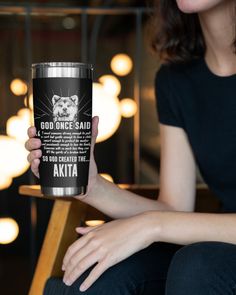 a woman holding up a travel mug with the words god once said, akita on it