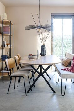 a dining room table with chairs and a bench in front of a large open window