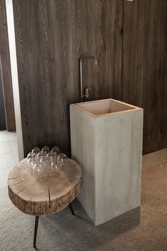 a wooden table with wine glasses on it next to a wall mounted faucet