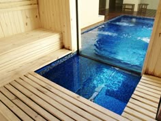 an indoor swimming pool with wooden steps leading up to it and a sauna in the middle