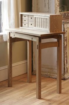 a wooden table with drawers on it in front of a window