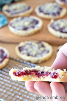 a hand holding up a cookie with cranberry toppings on it next to other cookies