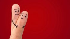 two fingers with faces drawn on them, one is smiling and the other is frowning