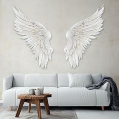 two large white angel wings on the wall above a couch