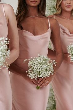 three bridesmaids in pink dresses holding baby's breath