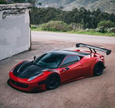 a red and black sports car parked in front of a building