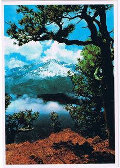 an image of a mountain with clouds in the sky and trees on the ground below