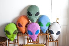 five alien pillows are lined up on a rack next to a wicker basket and chair