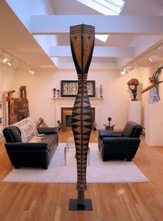 a living room filled with furniture and a tall wooden sculpture in the middle of it