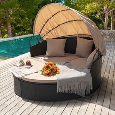 an outdoor daybed with sunflowers and pillows on the deck next to a swimming pool