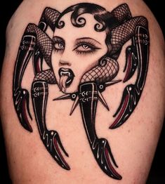 a woman's face with two large scissors in her mouth and an elaborate tattoo design on her thigh