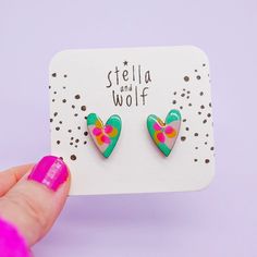 a pair of colorful heart shaped earrings sitting on top of a card