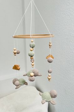 a crocheted sea turtle mobile hanging from a wooden rod in a white room