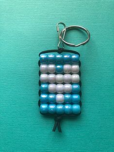 a keychain made out of plastic beads on a green surface with a black hook