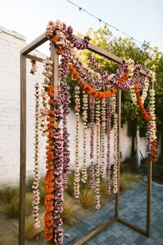 an outdoor ceremony with flowers and greenery hanging from the ceiling, along with brick walkway