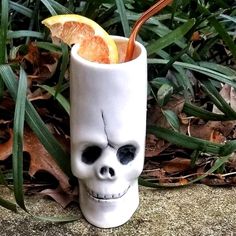 a skull shaped drink cup with an orange slice in it and a straw sticking out of the top