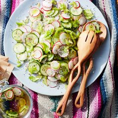 a white plate topped with cucumber and radishes next to a wooden spoon