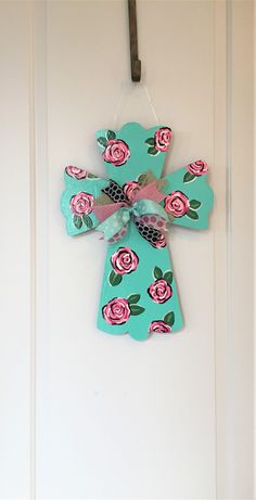 a wooden cross hanging on a door with flowers painted on the front and back of it