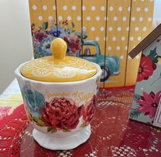 a cup with a yellow lid sitting on a table next to a small bird house