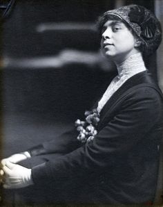 an old black and white photo of a woman wearing a hat with flowers on it