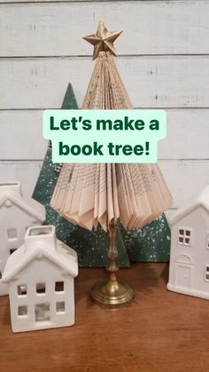 an open book is sitting on a table next to small houses and a christmas tree with the words let's make a book tree