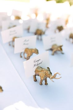 there are many small elephants on the table with place cards in their trunks and feet