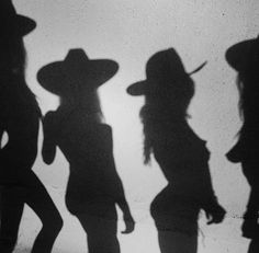 several silhouettes of people wearing hats and standing in front of a wall with the shadow of them