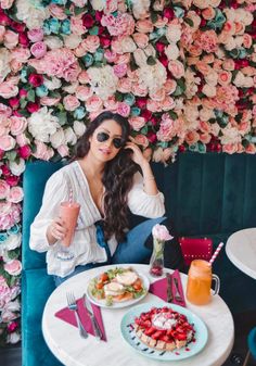 a woman sitting at a table with food and drinks