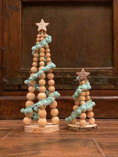 two small wooden christmas trees sitting on top of a wooden table next to each other