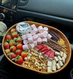 a basket filled with candy, marshmallows and strawberries