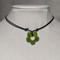 a necklace with a green flower pendant on a mannequin's neckline