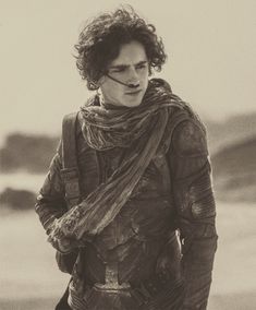 black and white photograph of a man with curly hair wearing a scarf on the beach