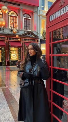 a woman standing next to a red phone booth