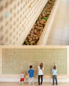 three children standing in front of a wall filled with nuts