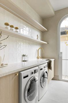 a washer and dryer sitting in a kitchen next to an open door with shelves above it