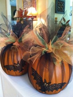 two pumpkins with bows on them sitting on a table