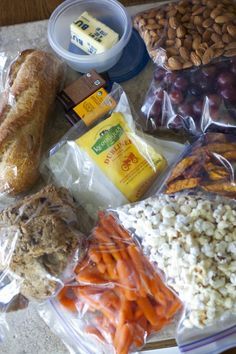 an assortment of food is sitting on a table with plastic wrappers and other items