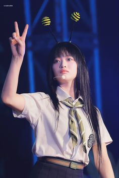 a woman with long black hair and two yellow pins on her head is making the peace sign